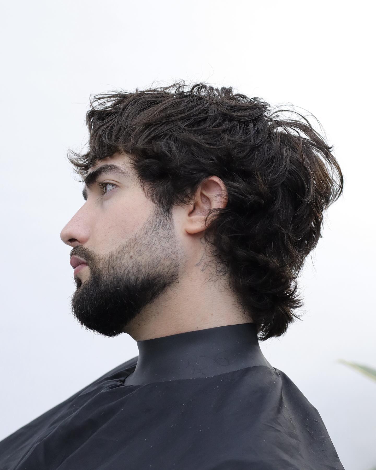 Side profile of a men’s wolf cut haircut with wavy layers and longer textured length at the back — classic male wolf cut style